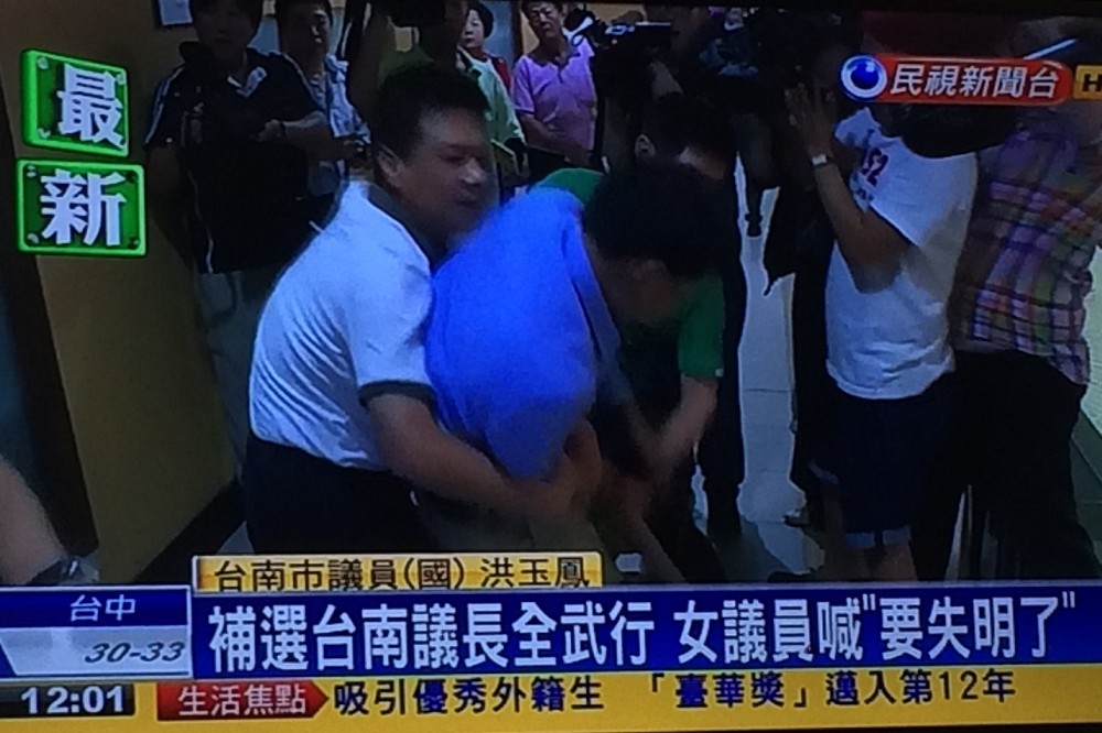 台南市議會開臨時會進行議長補選，國民黨團聚集大門前抗議違法開會，大門也遭人以鐵鍊鎖住，爆發流血衝突。（翻攝自民視新聞台）