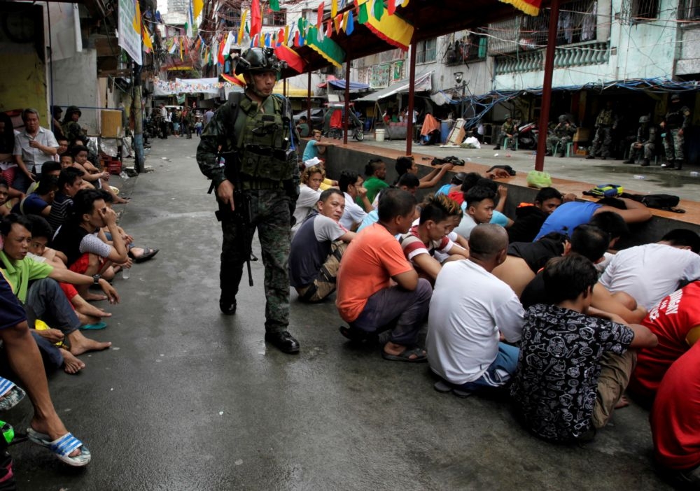 菲律賓警方掃蕩毒品行動結束後，民眾坐在地上等候處置。（湯森路透）