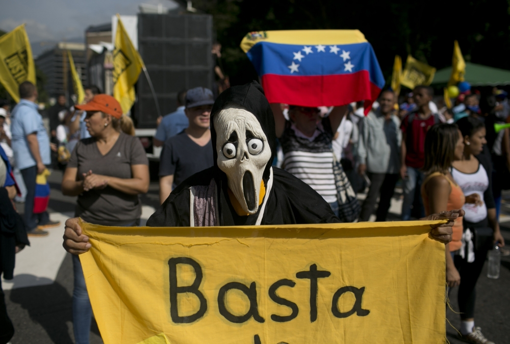 示威民眾高舉標語，上面以西班牙文寫著「夠了」。（美聯社）