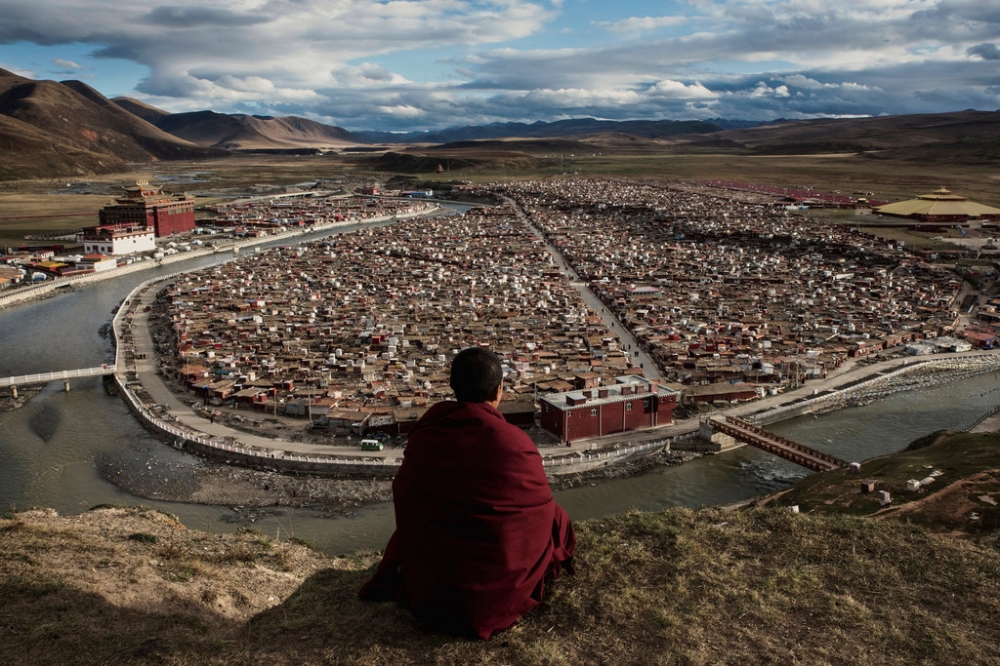 一名僧侶在亞青鄔金禪林的高處遠望，他腳下的棚戶區居住著數以千計的尼姑。  （紐約時報）