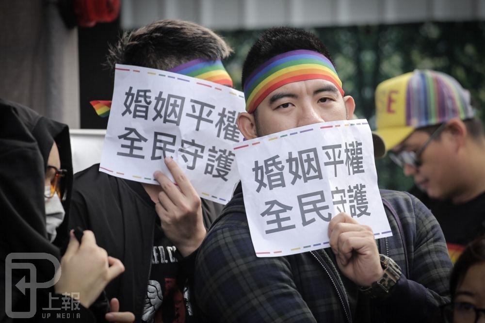 挺同婚方在頭上綁著彩虹布條，手舉「婚姻平權、全民守護」標語。（攝影：陳品佑）