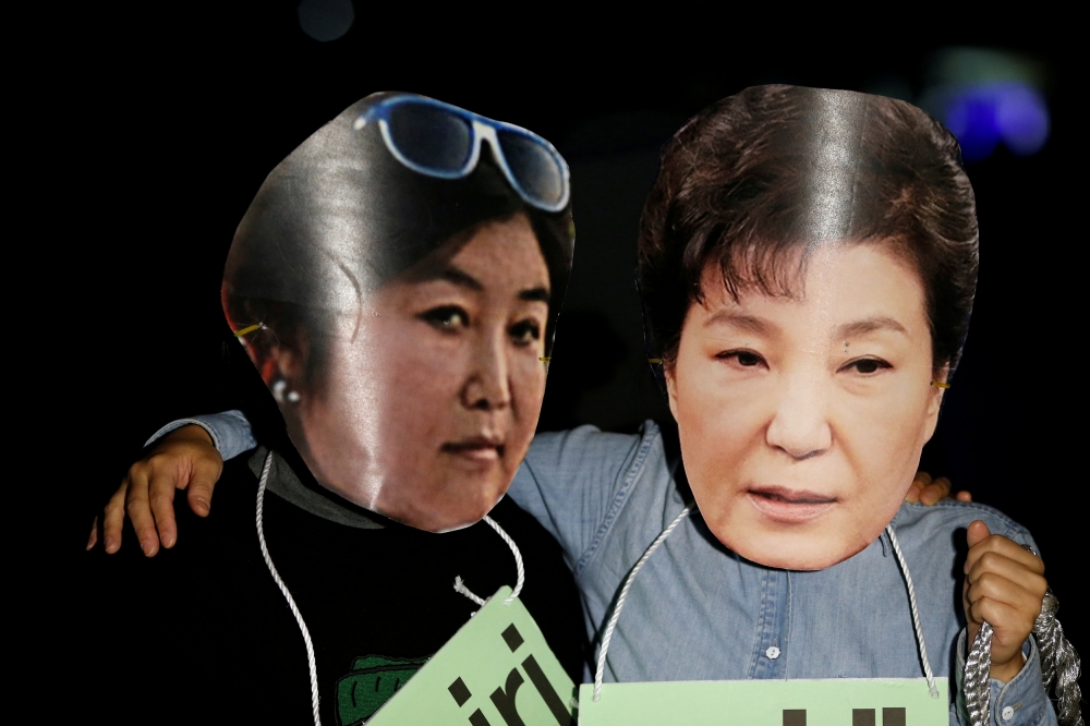 南韓民眾上街抗議，戴著崔順實與朴槿惠肖像製成的面具。（湯森路透）