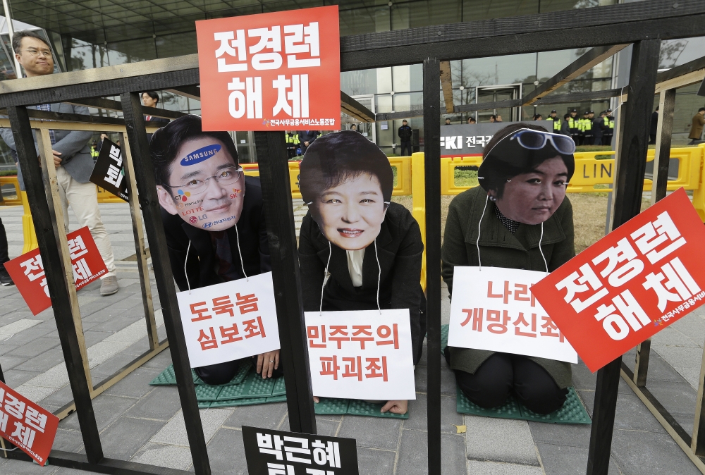 南韓民眾諷刺三星副會長李在鎔、朴槿惠與崔順實將成階下囚。（美聯社）
