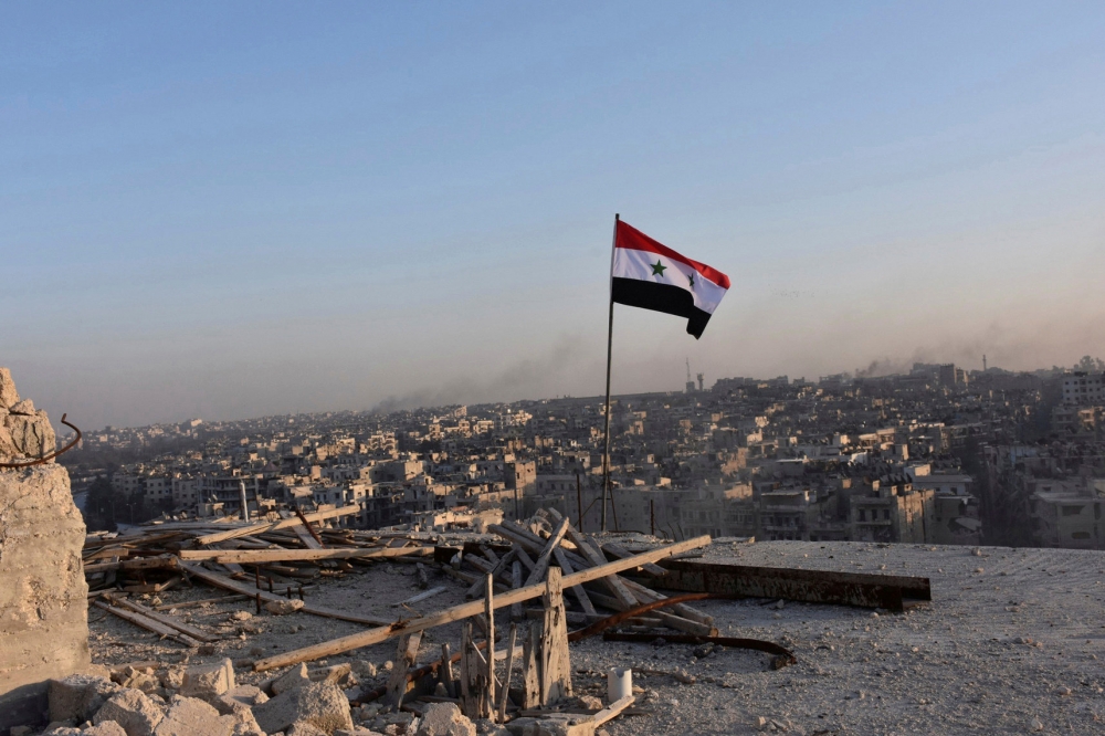 飄揚的敘利亞國旗，背後是阿勒坡東部的全景。（湯森路透）