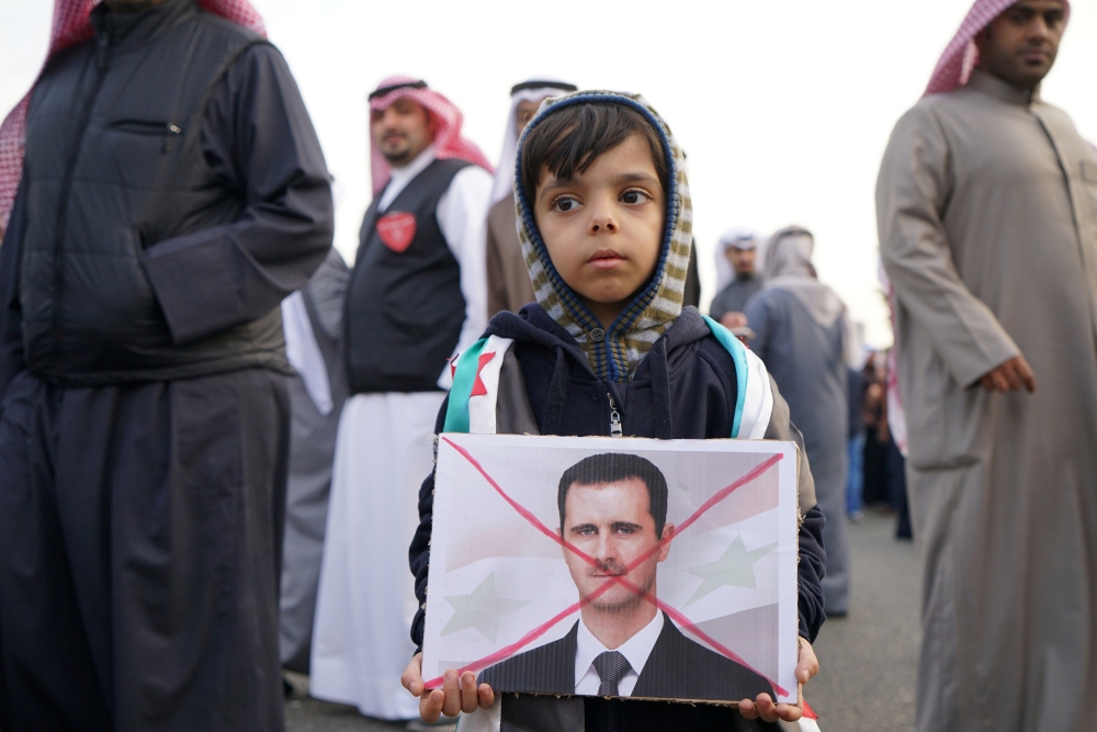 一名敘利亞孩童拿著反對阿塞德的文宣。（湯森路透）