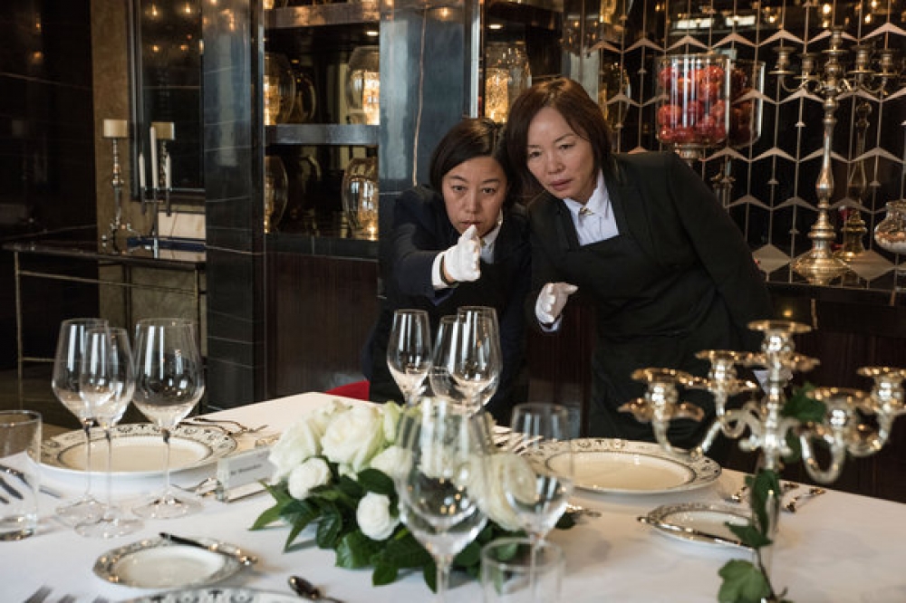 成都荷蘭國際管家學院中國分院的學生劉建敏（音，左）和張玲在檢查一個正式晚宴餐桌上的酒杯是否排齊。 （紐約時報）