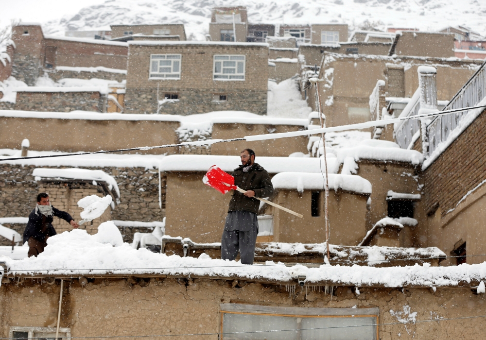阿富汗民眾忙著清除屋頂上的積雪。（湯森路透）