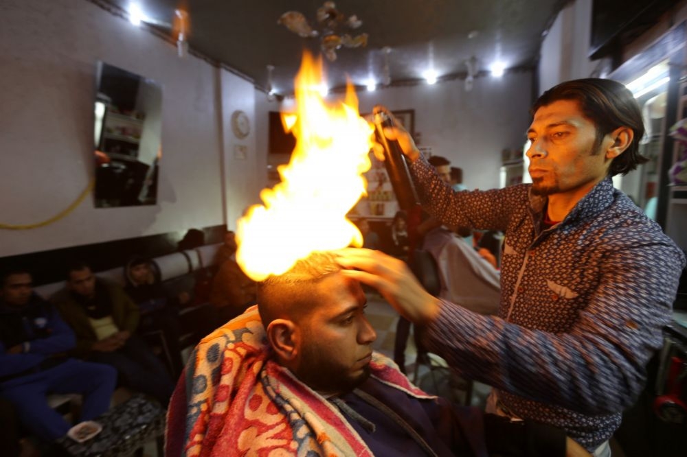 加薩走廊知名設計師歐德萬以火焰替顧客「燙」直頭髮。　　（湯森路透）