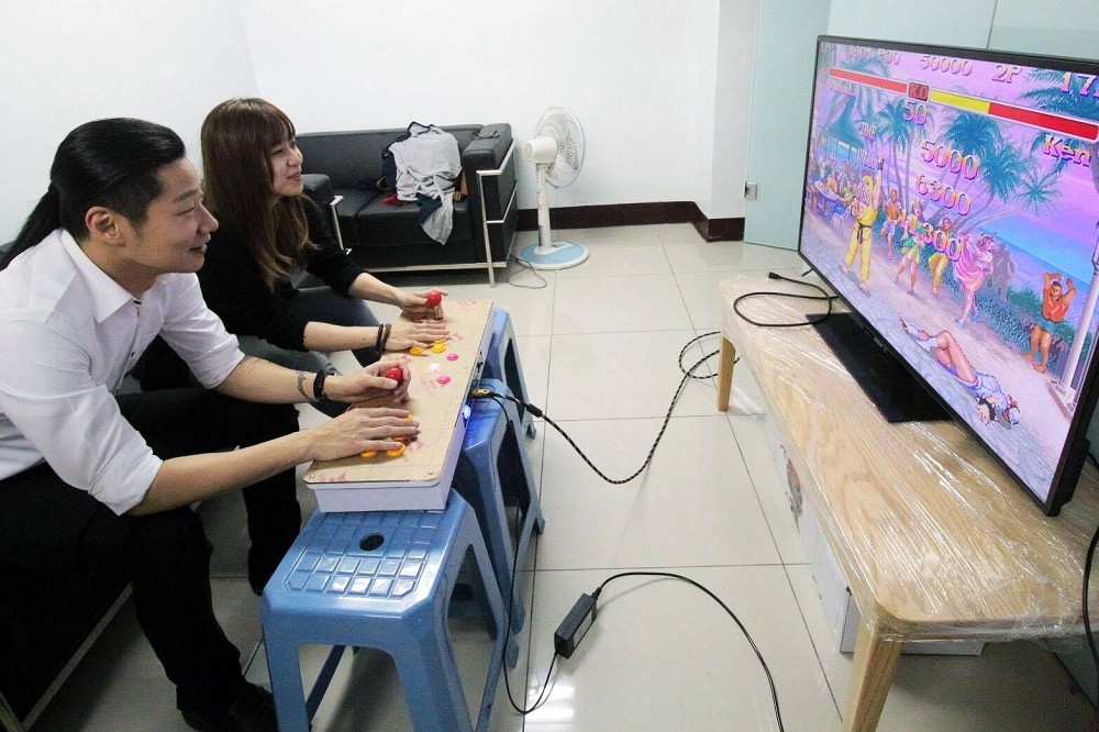 林昶佐近日刊登出一張與助理玩遊戲的照片，被眼尖的網友發現，他在玩的是一款名叫「月光寶盒」的盜版，仿街機電視遊戲機。（翻攝自林昶佐 Freddy Lim臉書）
