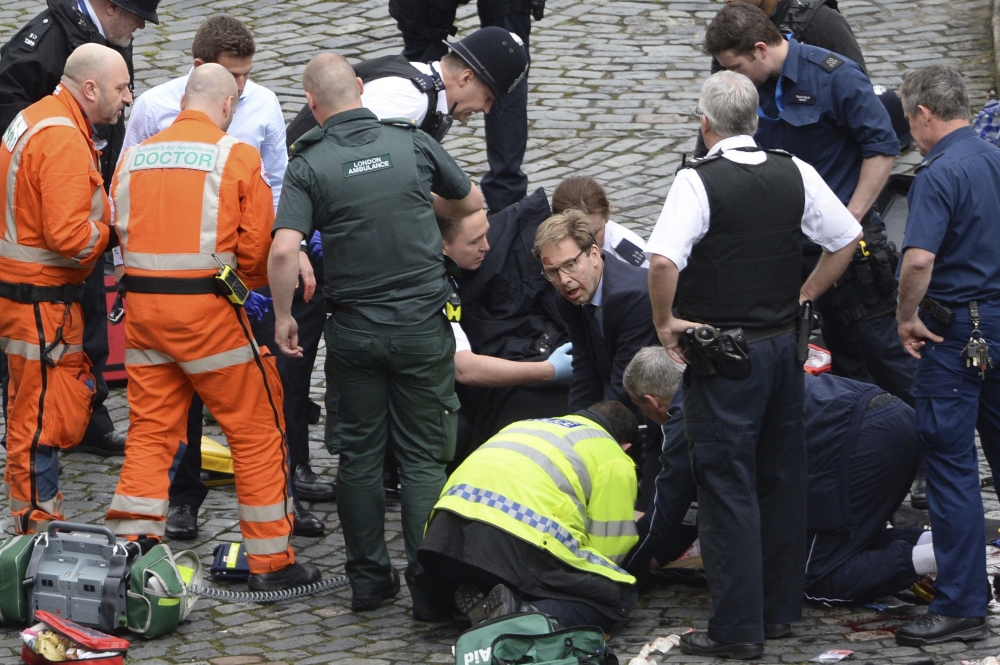英國議員艾伍德（戴眼鏡蹲者）22日在恐攻現場進行CPR。（美聯社）