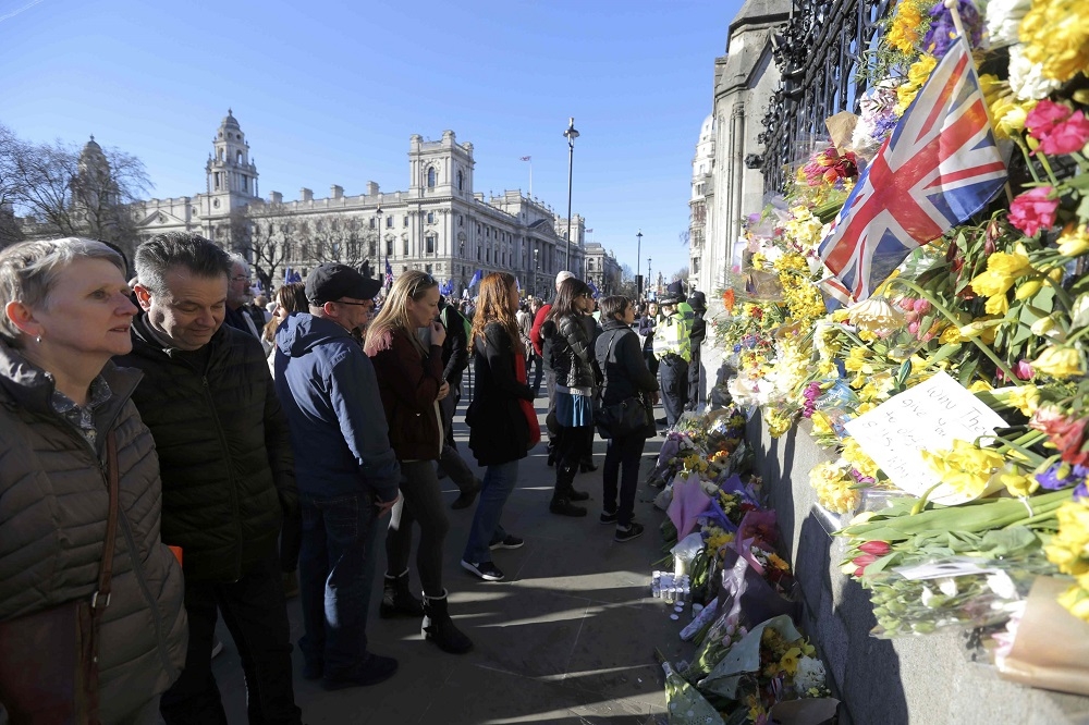 在22日的倫敦恐怖攻擊後，許多民眾在國會大廈的外牆擺上花束以表示哀悼。（湯森路透）