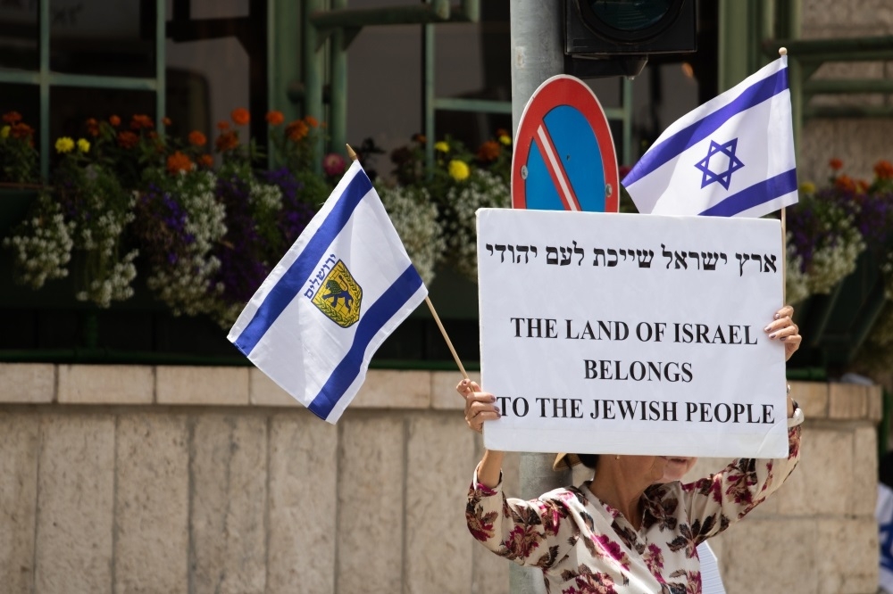 耶路撒冷街上，一名婦女高舉「以色列的土地屬於猶太人」的標語。（攝影：李隆揆）