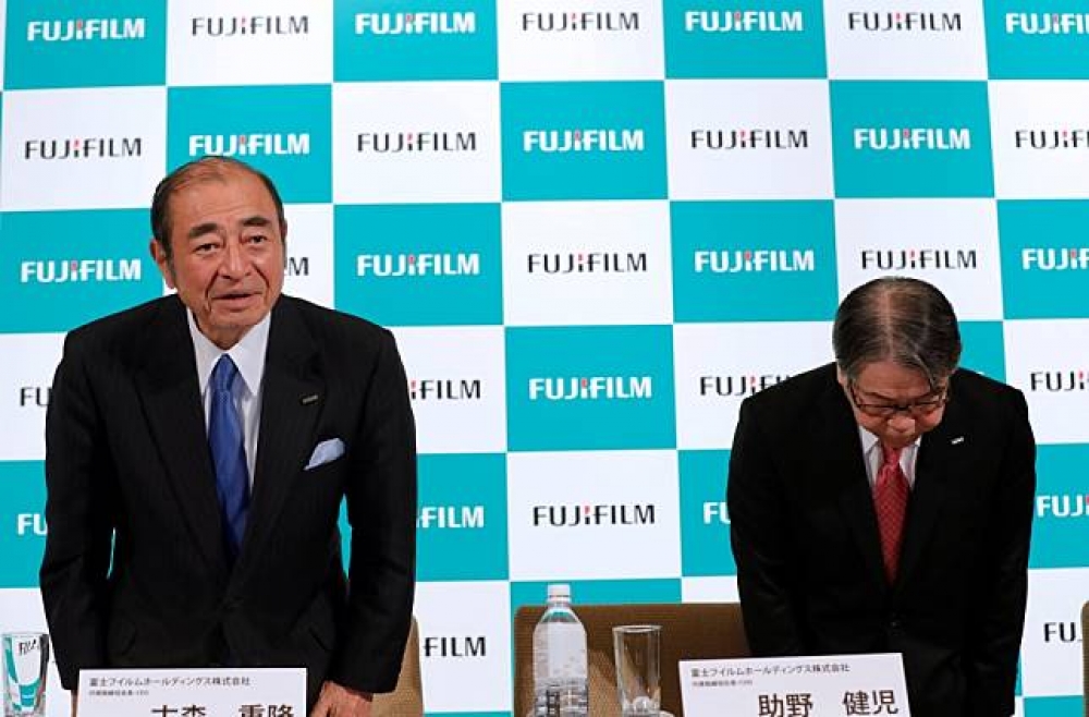 日本富士軟片控股執行長古森重隆（圖左），在31日記者會結束後鞠躬。（湯森路透）