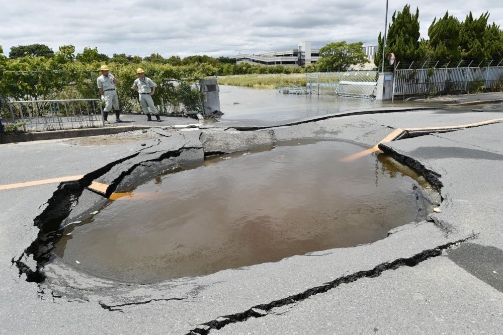 日本高槻市18日因地震路面凹陷形成的水坑。（湯森路透）