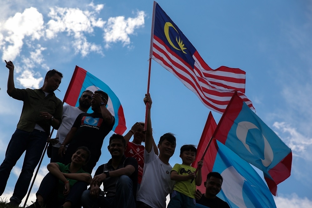 國會大選翌日，支持馬哈迪的民眾揮舞著「希望聯盟」的旗幟與馬來西亞國旗。（湯森路透）