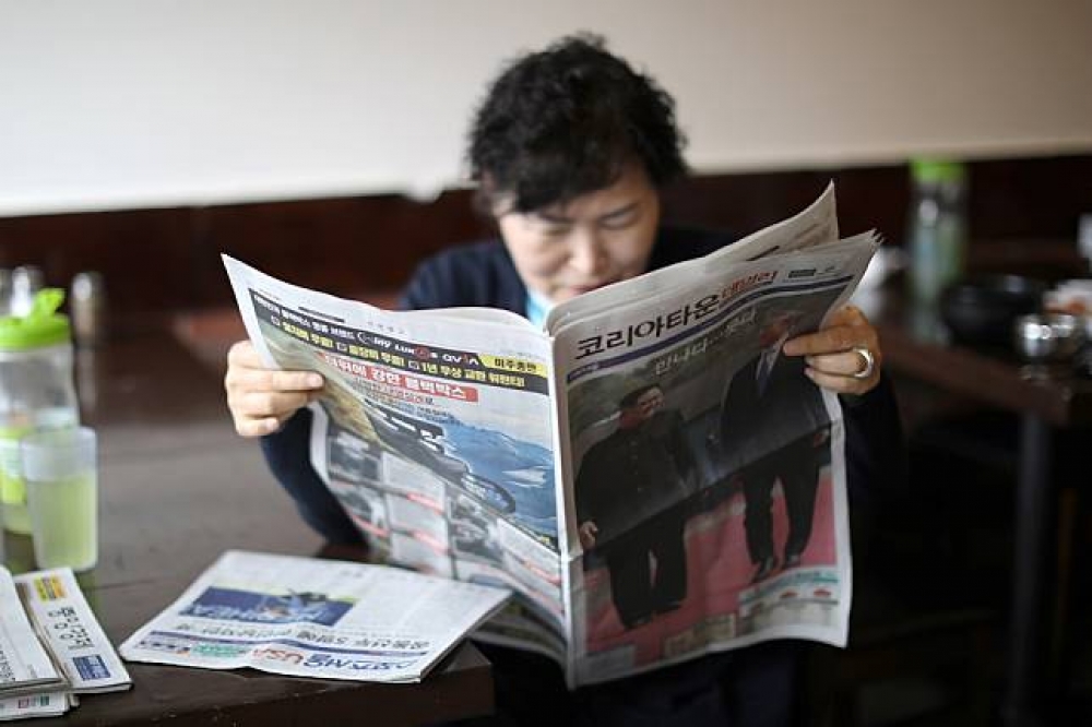 一名韓僑婦女在美國洛杉磯透過報紙了解「文金會」消息。（湯森路透）