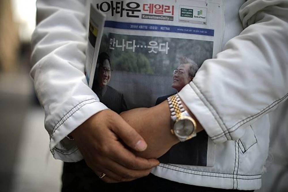 南韓民眾手持報導兩韓峰會的報紙。（湯森路透）