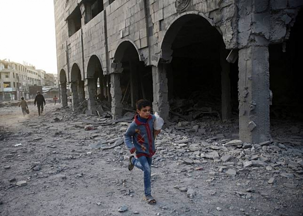敘利亞東古塔地區，一名男童跑過殘破的建築。（湯森路透）