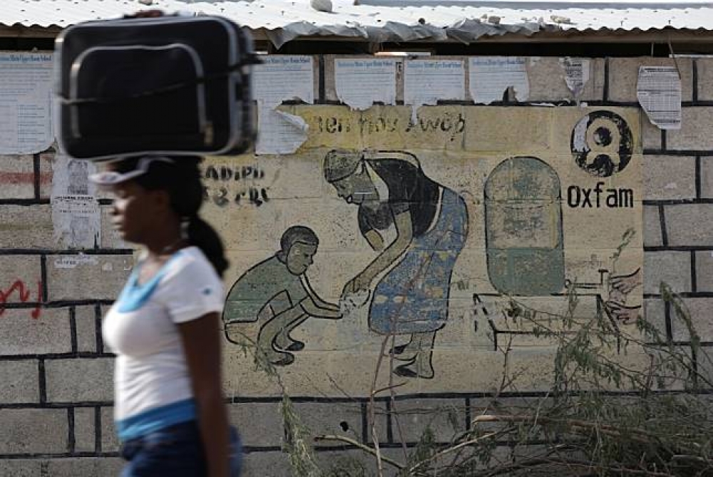 海地震災災民收容所前，一面牆上印有樂施會（Oxfam）的標誌。（湯森路透）