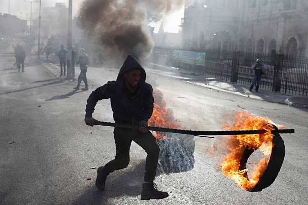 巴勒斯坦示威民眾拿起燃燒的路障。（湯森路透）