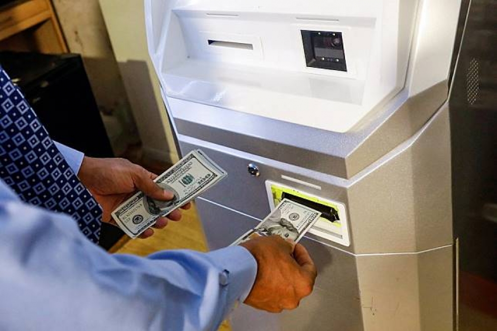 紐約比特幣中心（ Bitcoin Center NYC），一名男子正在將錢匯入比特幣ATM中。（湯森路透）