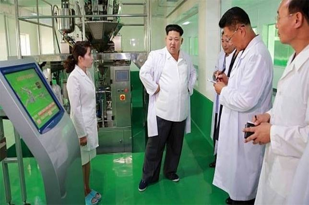 北韓領導人金正恩（中）近期積極發展生化武器。圖為金正恩2015年視察「平壤生物技術研究所」。（湯森路透）