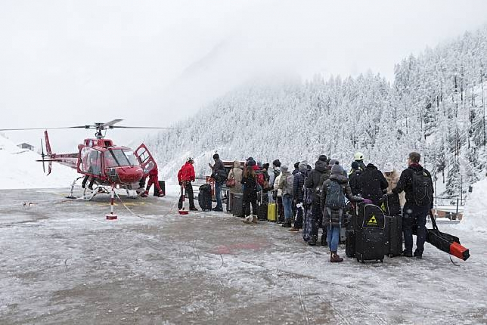 瑞士策馬特降大雪，旅客正排隊搭乘直升機前往附近的城鎮拉龍（Raron）。（美聯社）