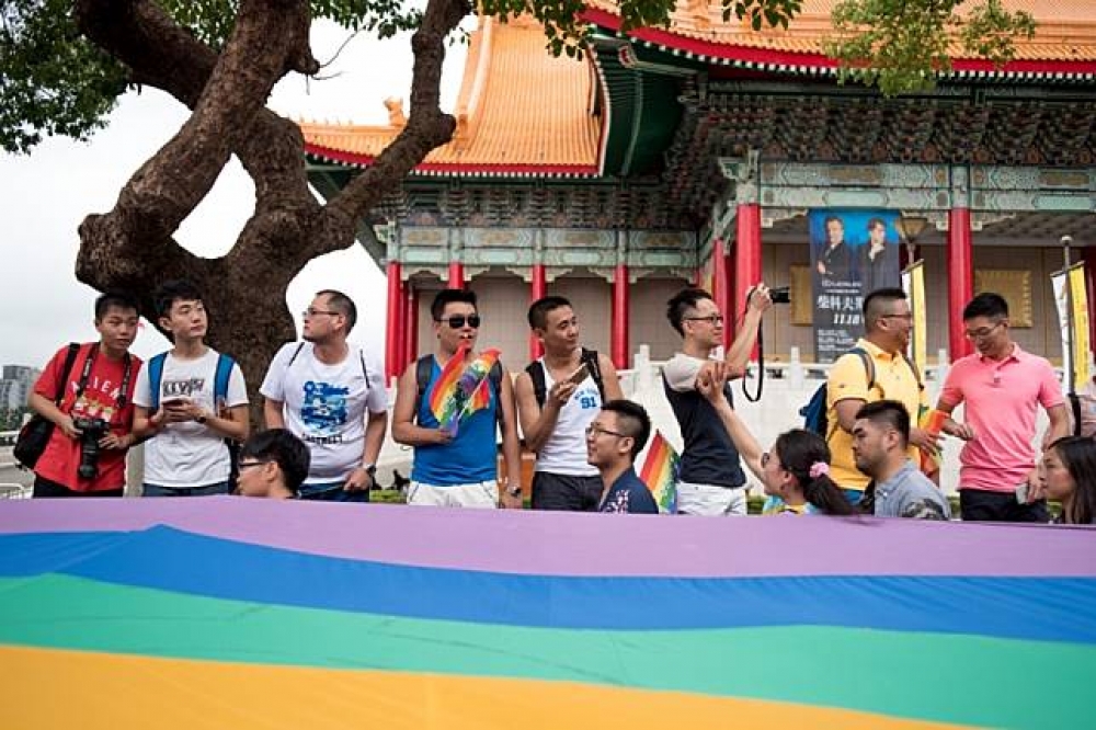 圖為去年10月29日同志大遊行，民眾手拿彩虹旗為同志權利發聲。（攝影者：李昆翰）