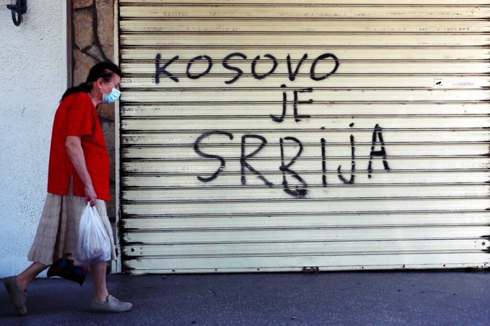 一名婦女路過寫著「科索沃是塞爾維亞」的塗鴉。（美聯社）