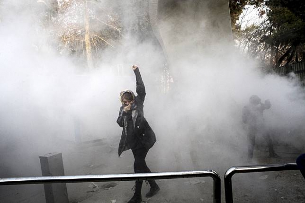伊朗大學生參與示威，現場瀰漫警方投擲的催淚瓦斯的煙霧。（美聯社）