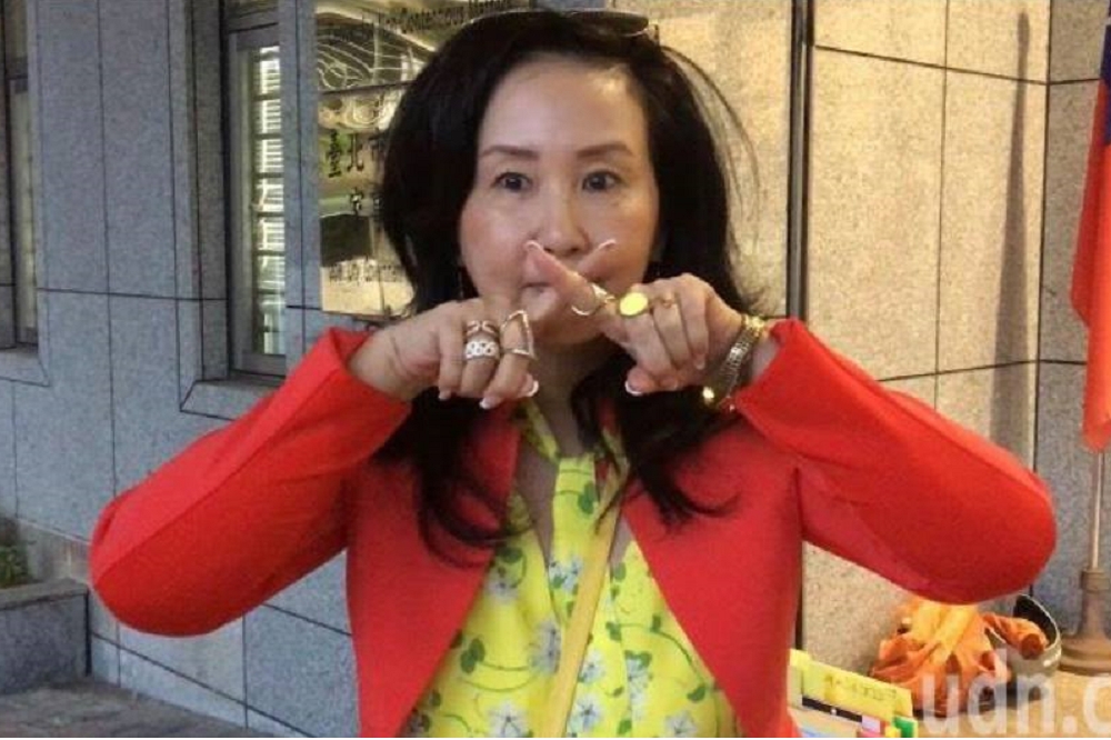 李文在26日的遺產官司庭訊後，在媒體前，用手指在嘴上比了個叉叉，表示法院讓她簽屬「封口協議」，自己與李戡對外都不能對案件做任何說明。（圖片取自李文臉書）