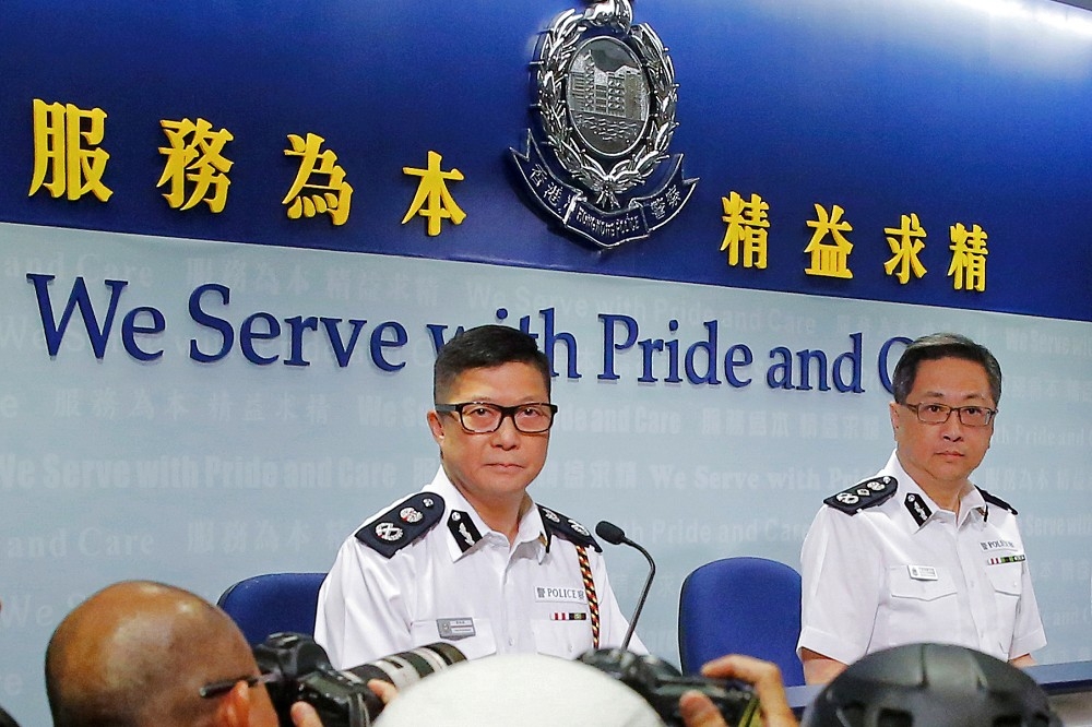 香港新任警務處處長鄧炳強（左，時任副處長）6月與時任警務處處長盧偉聰（右）出席記者會。（湯森路透）