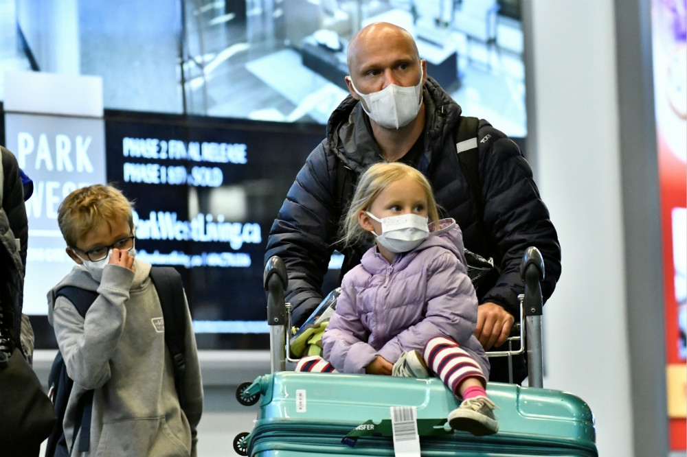 返回加拿大溫哥華機場的外籍人士，一家三口戴上口罩防禦流感與新型肺炎。（湯森路透）