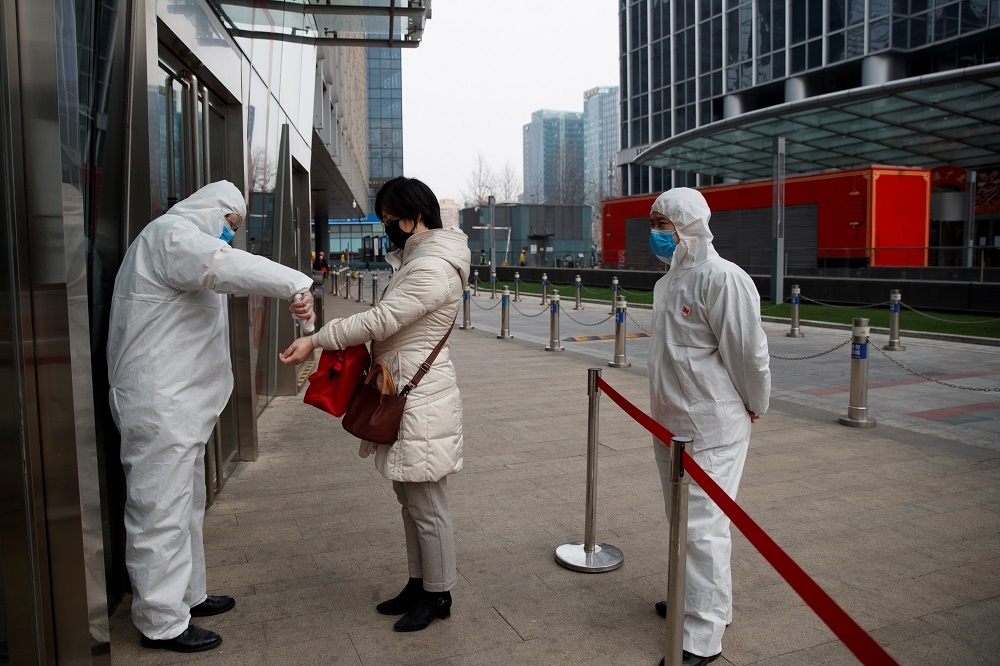 中國北京有一名工作人員正在為民眾測量體溫。（湯森路透）