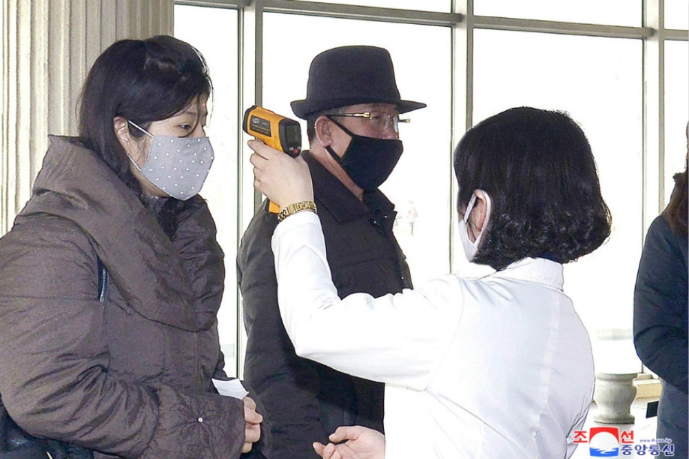 北韓防疫人員替訪客測量體溫。（湯森路透）
