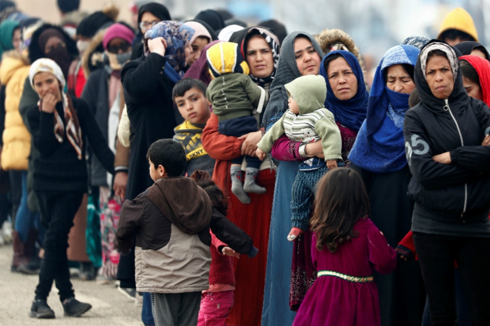 大批滯留在土耳其與希臘邊境的難民，排隊領取食物供給。（湯森路透）