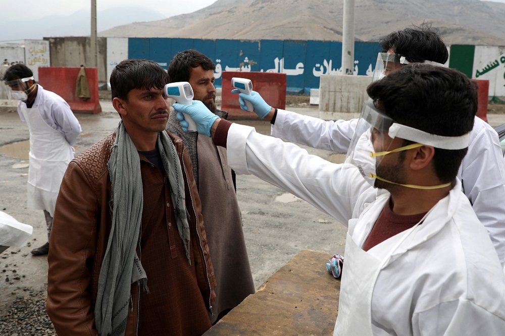 阿富汗醫療人員為民眾測量體溫。（湯森路透）