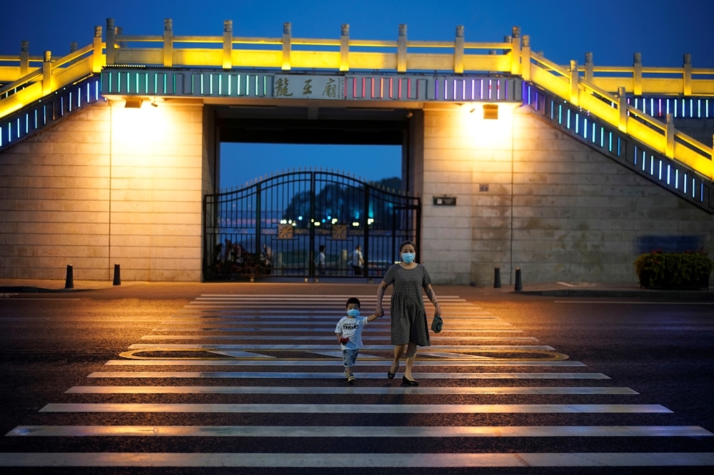一個婦女牽著小孩走在武漢街頭（湯森路透）
