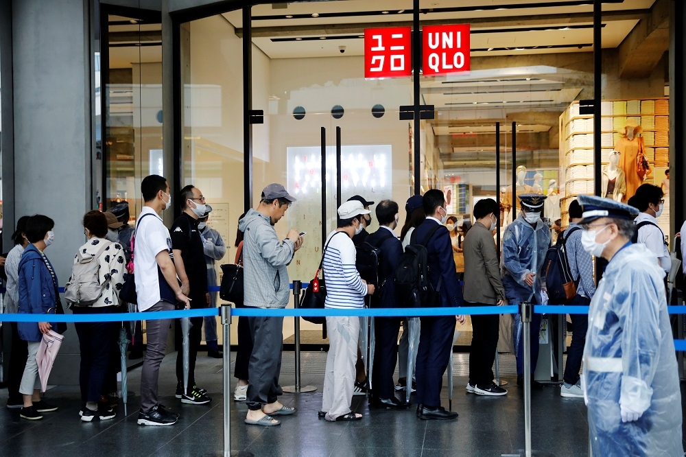 日本民眾戴口罩排隊等候進入商家。（湯森路透）