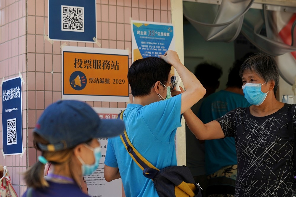 香港11日民主派初選，民眾在投票所外測量體溫。（湯森路透）