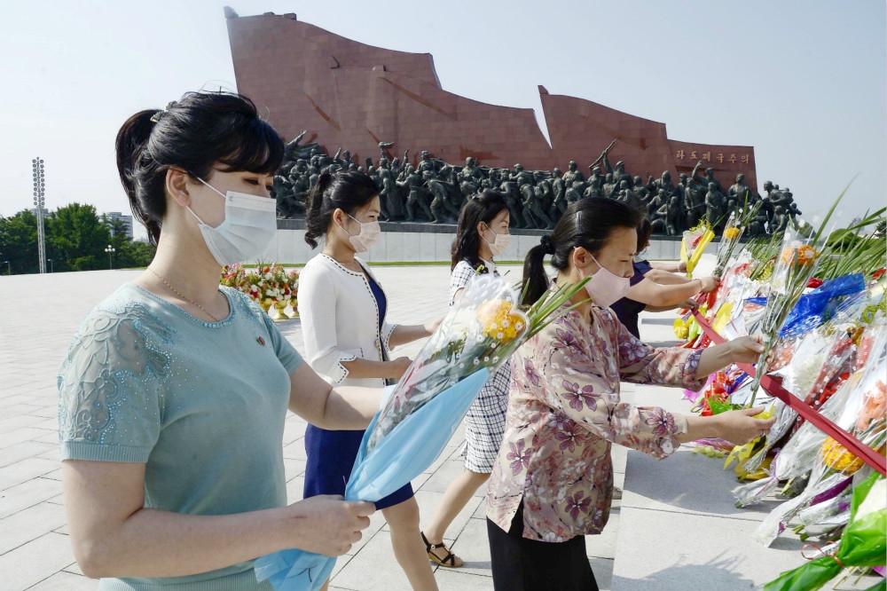 戴口罩向人民軍紀念碑獻花的北韓民眾。（湯森路透）