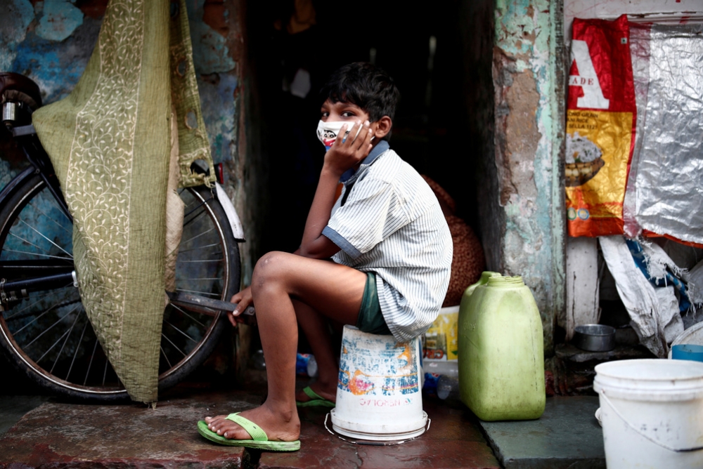印度防疫全境封鎖，新德里貧民窟小男孩帶著口罩防疫。（湯森路透）