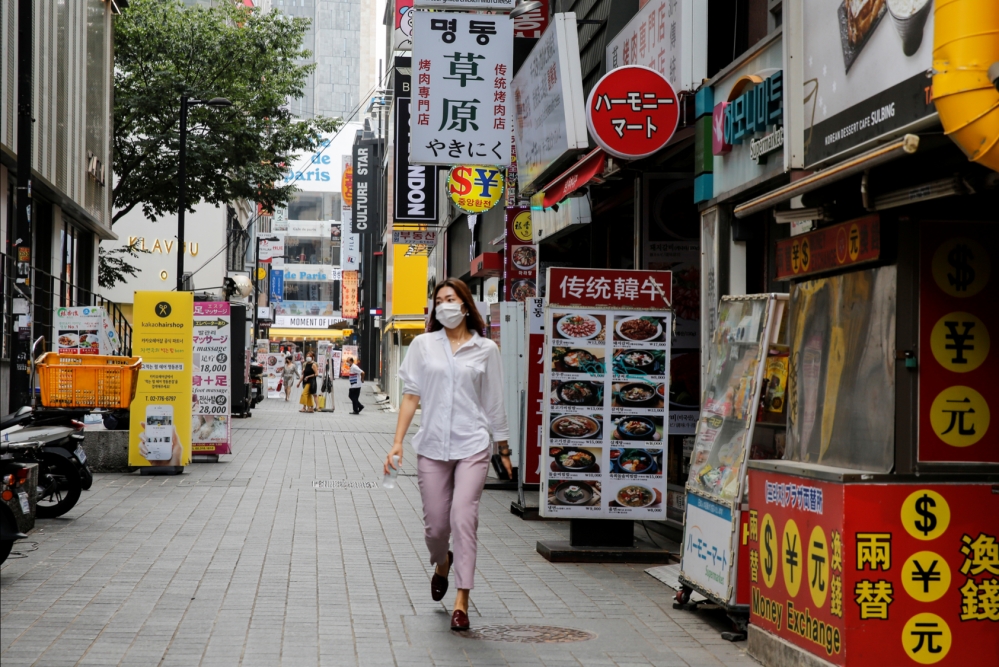 一名戴著口罩的女性在南韓首爾明洞購物區行走。（湯森路透）