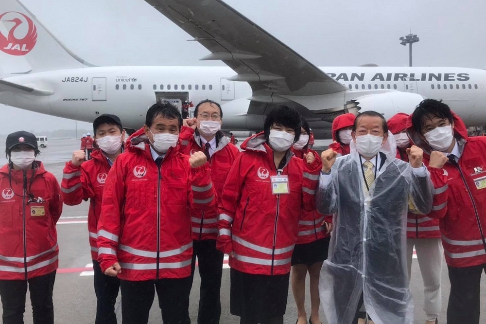 日本提供給台灣的 124 萬劑 AZ 疫苗，在雙方人員的見證下啟程飛往台灣，右二穿西裝及雨衣者為駐日代表謝長廷。 （台北駐日經濟文化代表處新聞組提供）