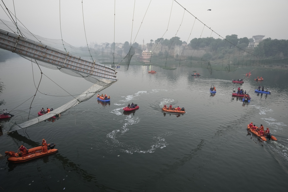 吊橋崩塌意外發生後，救難人員駕駛小艇在河面展開搜救。（美聯社）