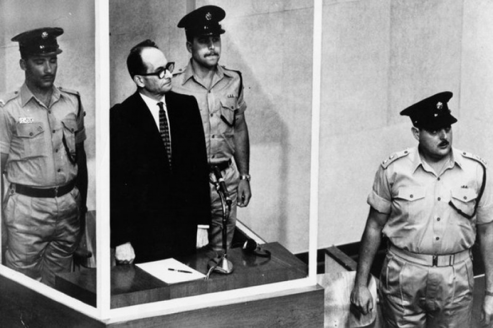 納粹高官艾希曼（Adolf Eichmann）於防彈玻璃後面受審。（美聯社）
