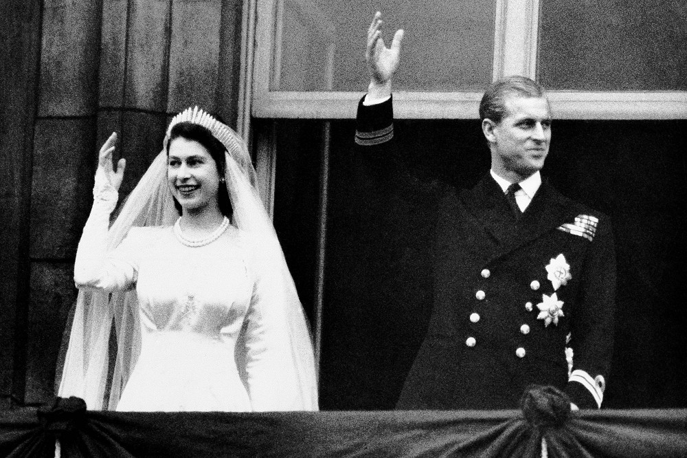1947年11月20日，伊莉莎白公主（左）、愛丁堡公爵菲利普（右）於婚禮後，在白金漢宮陽台上向人群揮手致意。（美聯社）