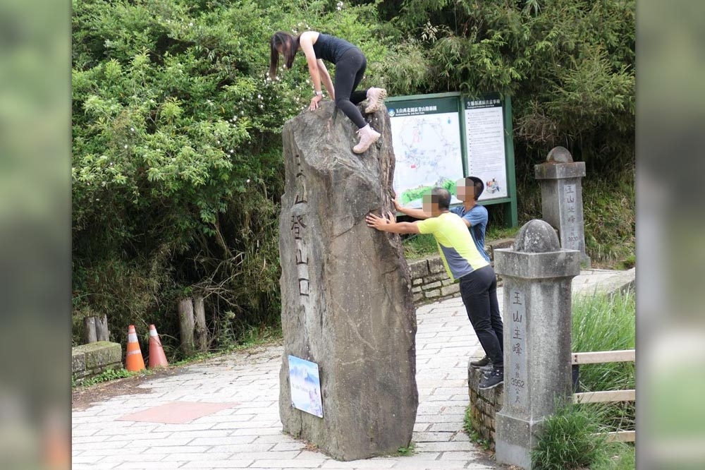 一名6女子擅自攀爬玉山登山口石碑頂，網友看到都替她捏把冷汗。（翻攝自登山通報站／Lin Cheng臉書）
