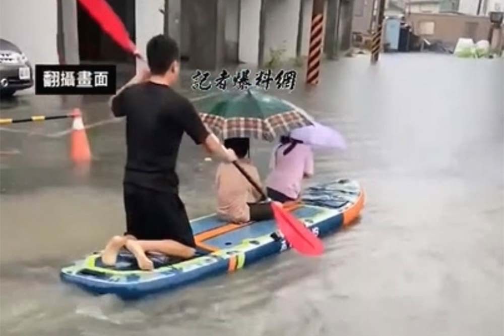 台南因暴雨多處低窪地區淹水，有民眾苦中作樂拿出立式划槳（SUP）載著小孩出門。（翻攝自記者爆料網）