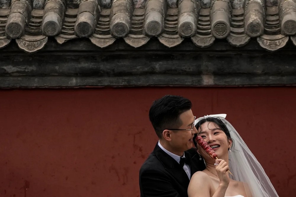 中國生育率與結婚率均下滑，一些地方政府祭出激勵措施。圖為北京一對新人拍婚紗照。（資料照片／美聯社）